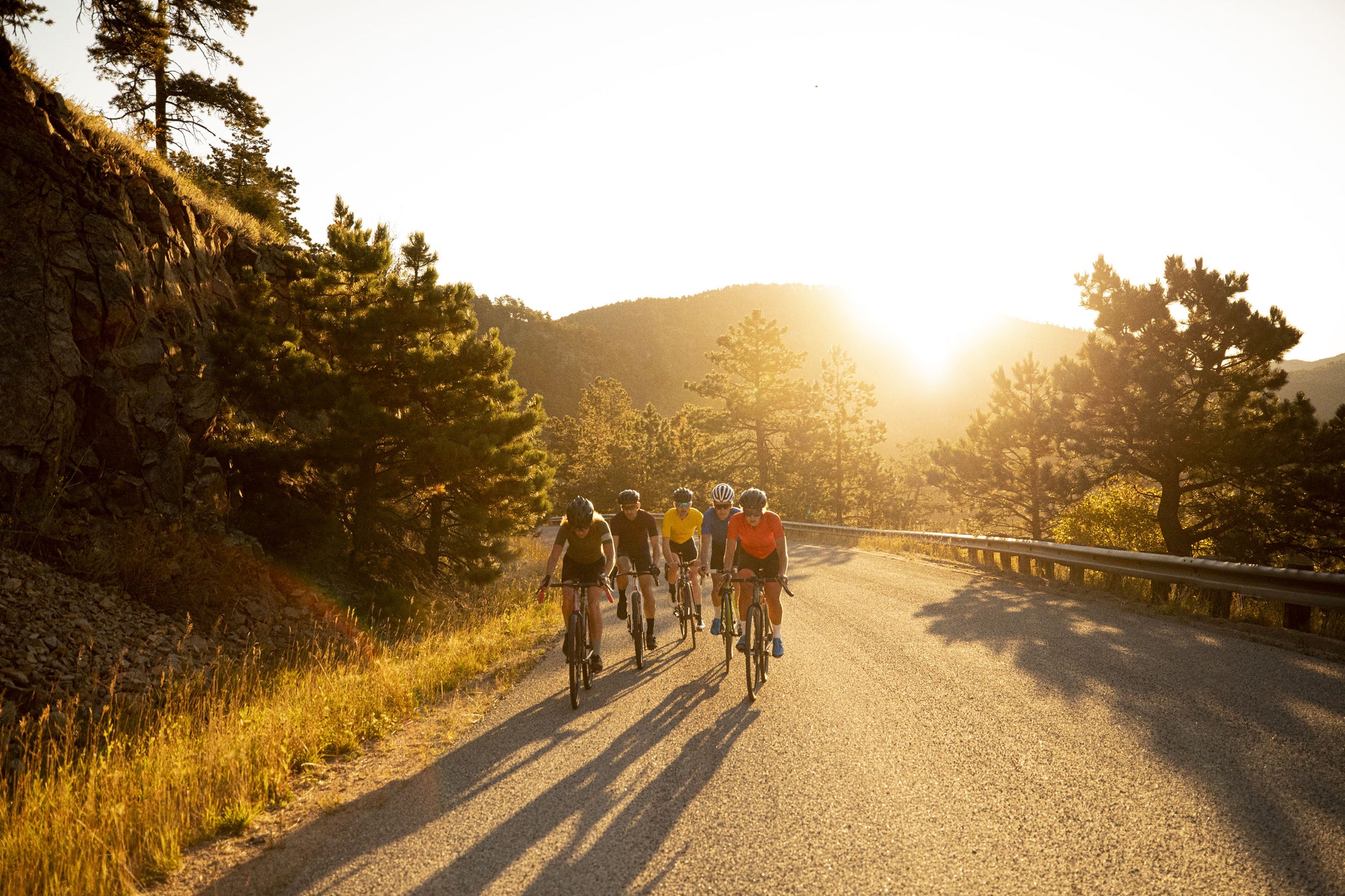 Cyclists climbing a road at sunrise